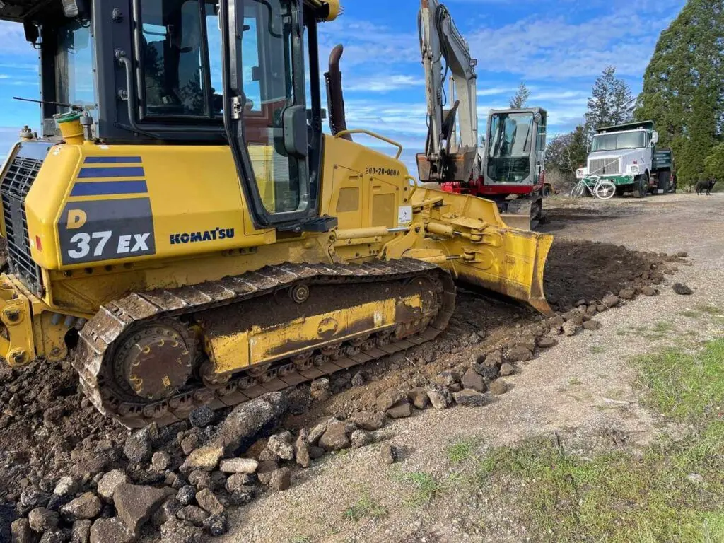 Komatsu excavator performing precision grading and site preparation on rocky Bay Area property